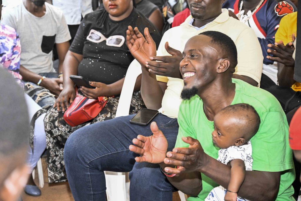 One of the beneficiary with his child attending the  handing over 36 boda bodas that is, 3 bikes for each of the 12 SACCOS in the Kampala Ghetto Structures, the State House Comptroller was fulfilling the pledge made by President Yoweri Kaguta Museveni, the handover of the Boda Bodas took place in Bwaise- Kawempe Division in Kampala on the 4th September 2024. Photo by PPU/ Tony Rujuta.