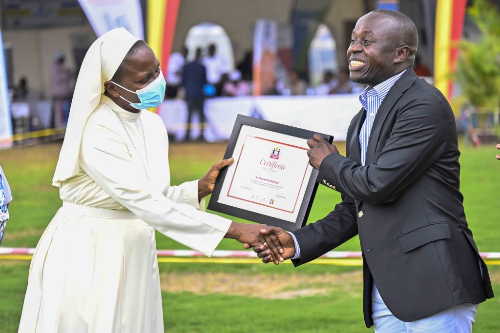 State Minister for Sports Peter Ogwang handing over an award to Sr. Maxiensia Babirye for exemplary service and innovation in developing and improving education in Uganda -2024 during the World Teacher’s Day Celebrations at Lugogo, Kampala on the 19th October 2024. Photos by PPU/Tony Rujuta.