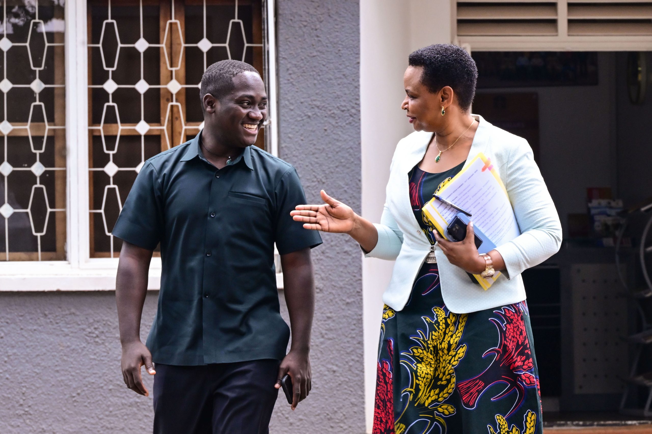 Head of State House Investors Protection Unit Col Edith Nakalema shares a light moment with Makerere University Guild president Vincent Lubega Nsamba at her offices in Nakasero on Friday PPU Photo