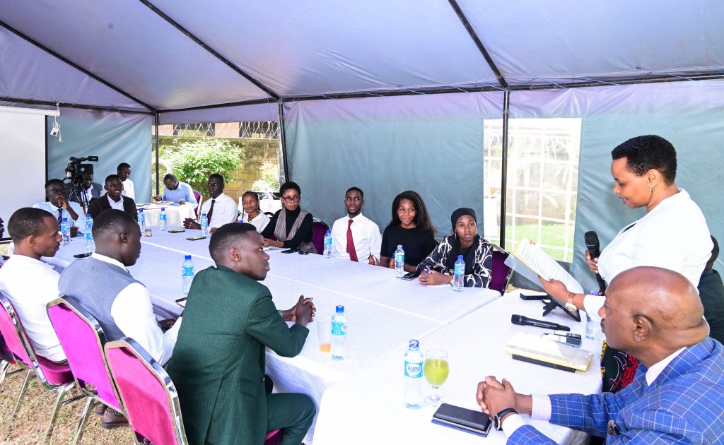 Head of State House Investors Protection Unit Col Edith Nakalema shares a light moment with Makerere University Guild president Vincent Lubega Nsamba at her offices in Nakasero on Friday PPU Photo